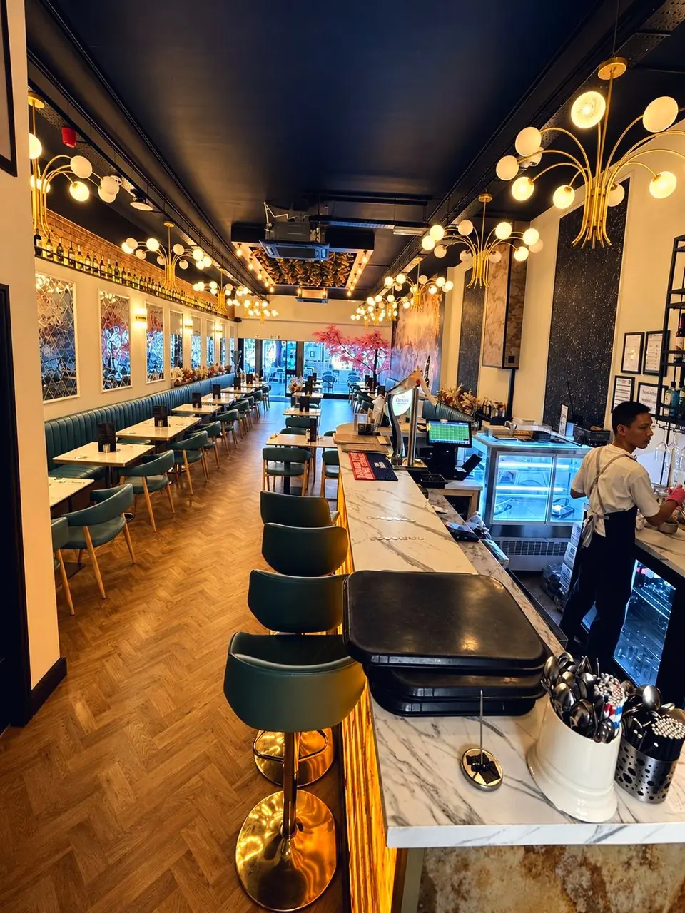 The counter at work down Jenny's long room, chandeliers overhead and blossom at the far end