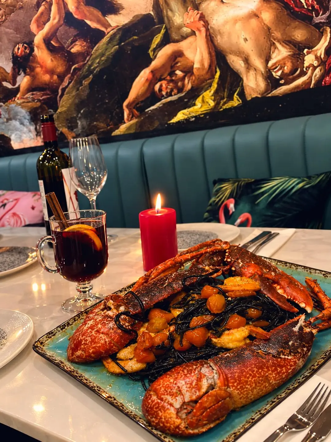 Lobster on a turquoise plate by candlelight, mulled wine beside it, under Jenny's painted sky