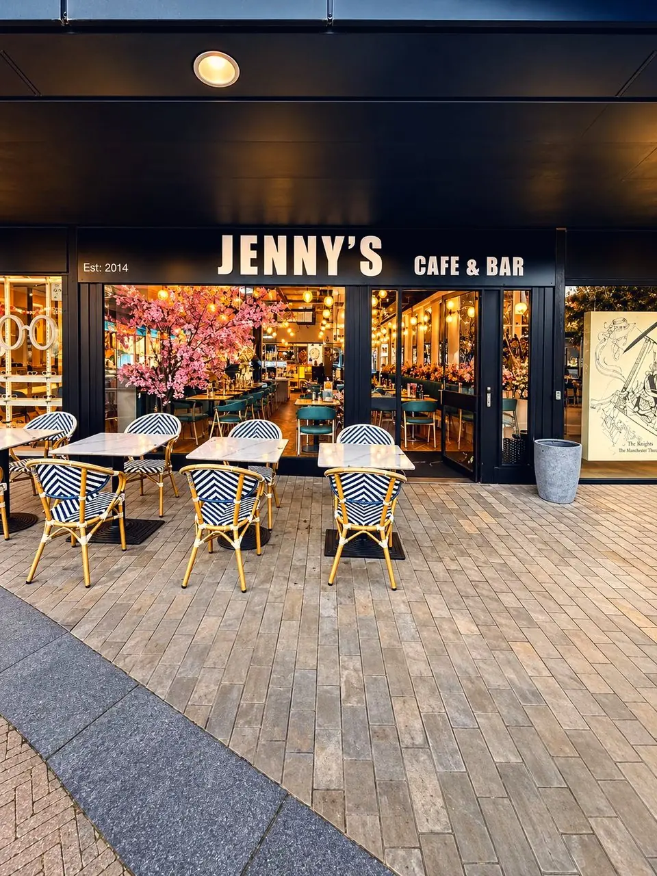 Jenny's on Stanley Square, the sign lit, chairs out on the square